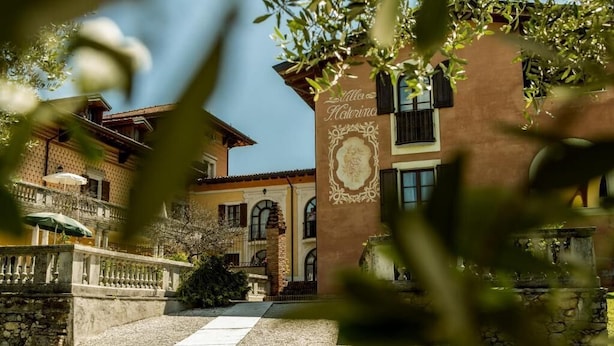 Un edificio tradicional con fachada de piedra, una entrada central y un letrero decorativo sobre la puerta.