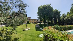 A well-maintained garden with a pool, a building with a yellow facade, and a clear sky. - Villa Santa Caterina - bright three-room apartment on the ground floor (Manerba del Garda)