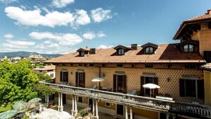 A building with a tiled roof, balconies, and a courtyard with outdoor furniture.