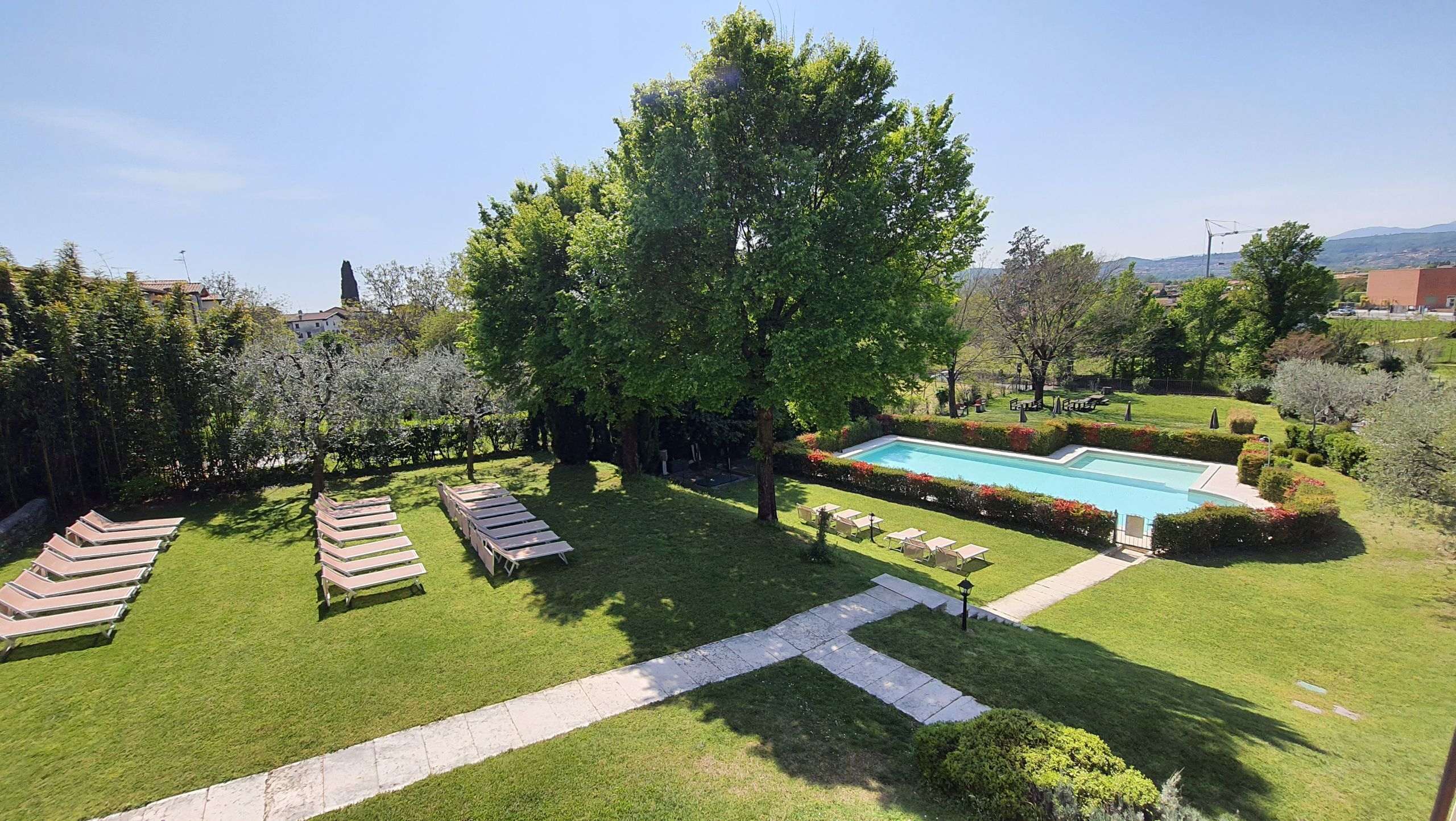 Un espace piscine doté de chaises longues, d’une pelouse bien entretenue et offrant une vue dégagée sur le paysage environnant.