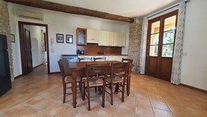 Eine Küche mit Esstisch, Stühlen, einem Kühlschrank und einer Steinwand.