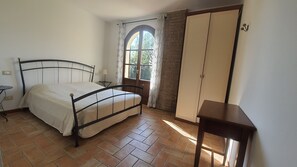 Een slaapkamer met een bed, een kledingkast, een tafeltje en een raam met gordijnen.