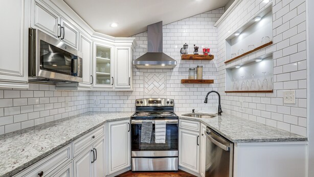 Una cocina con armarios blancos, una estufa de acero inoxidable y un microondas.