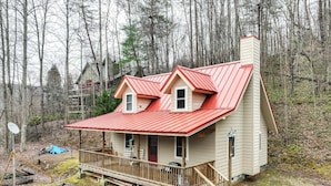A two-story cabin with a red roof, a wooden deck, and a chimney. - Santeetlah Lake Retreat w/ Dock: Walk to Water! (Robbinsville)