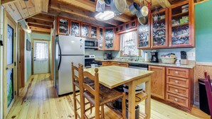 A kitchen with wooden cabinets, a refrigerator, a microwave, and a dining table with chairs. - Santeetlah Lake Retreat w/ Dock: Walk to Water! (Robbinsville)
