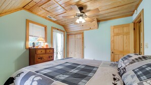 A bedroom with a wooden ceiling, a bed with a checkered bedspread, a dresser, and two doors. - Santeetlah Lake Retreat w/ Dock: Walk to Water! (Robbinsville)