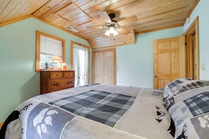 Un dormitorio con techo de madera, una cama con colcha a cuadros, un aparador y dos puertas.