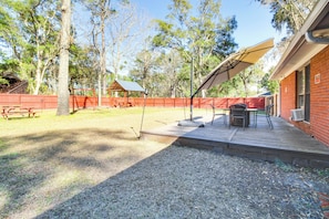 Un patio trasero con terraza de madera, mesa de picnic y zona de estar techada.