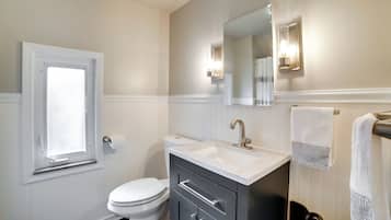 A bathroom with a toilet, sink, and mirror.