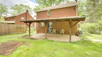 A brick house with a covered patio area, two chairs, and a wooden fence.