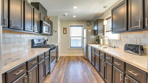 A modern kitchen with dark cabinets, a stainless steel refrigerator, a microwave, and a toaster. - Galveston Vacation Home: 2 Mi to Galveston Beach! (Galveston)