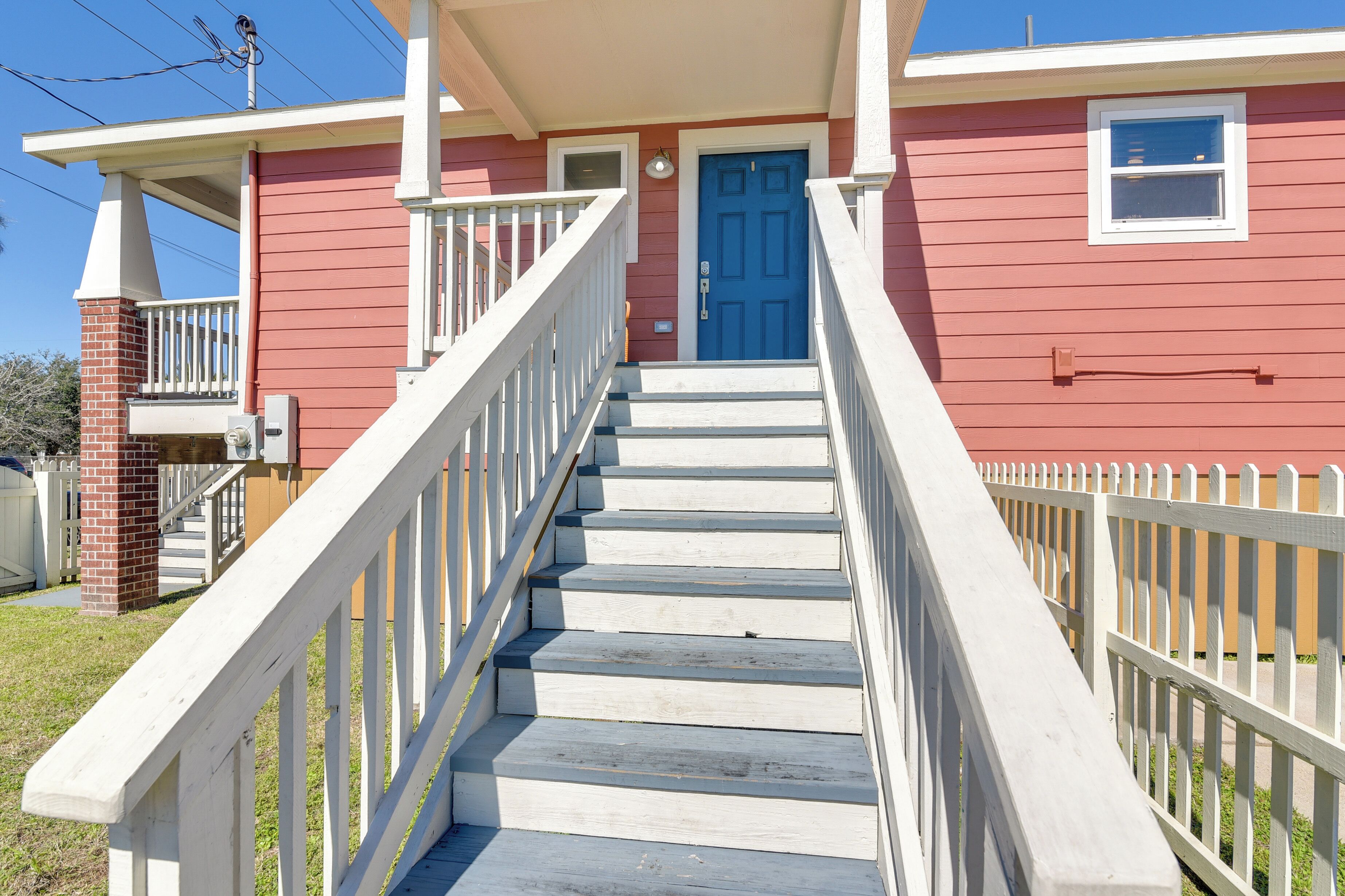 A red house with white railings and a blue door.