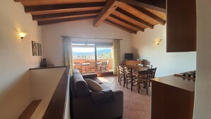 Un espace de vie confortable comprenant un canapé, une table à manger et des chaises, un balcon avec vue et un coin cuisine équipé d’une cuisinière.