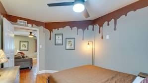 Ein Schlafzimmer mit Bett, Schreibtisch, Stuhl, Deckenventilator und einer Wand mit Wischlacker-Design.