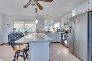 A modern kitchen with a central island, stainless steel appliances, and pendant lighting.