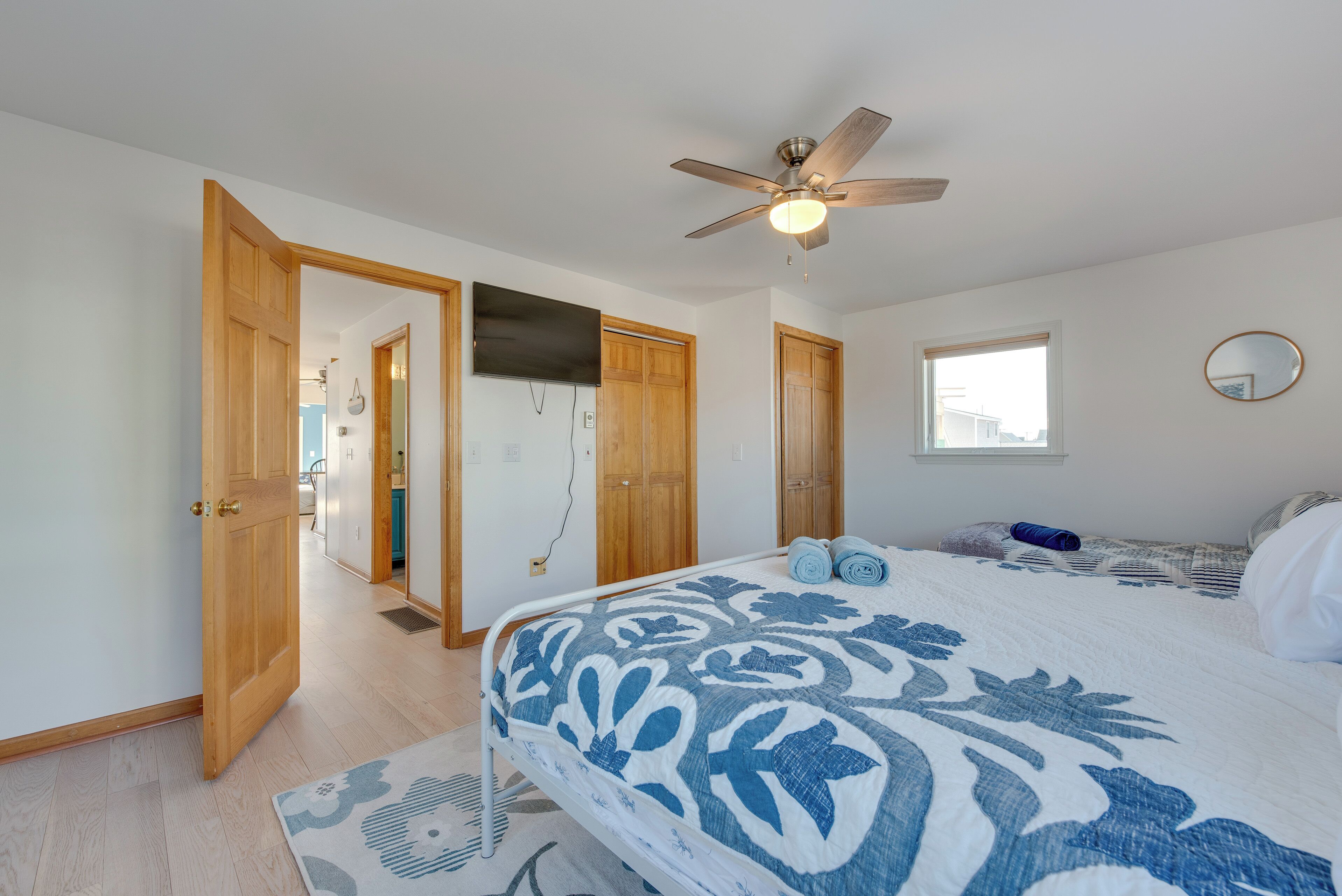 Un dormitorio con cama, ventilador de techo, ventana y puertas de madera.
