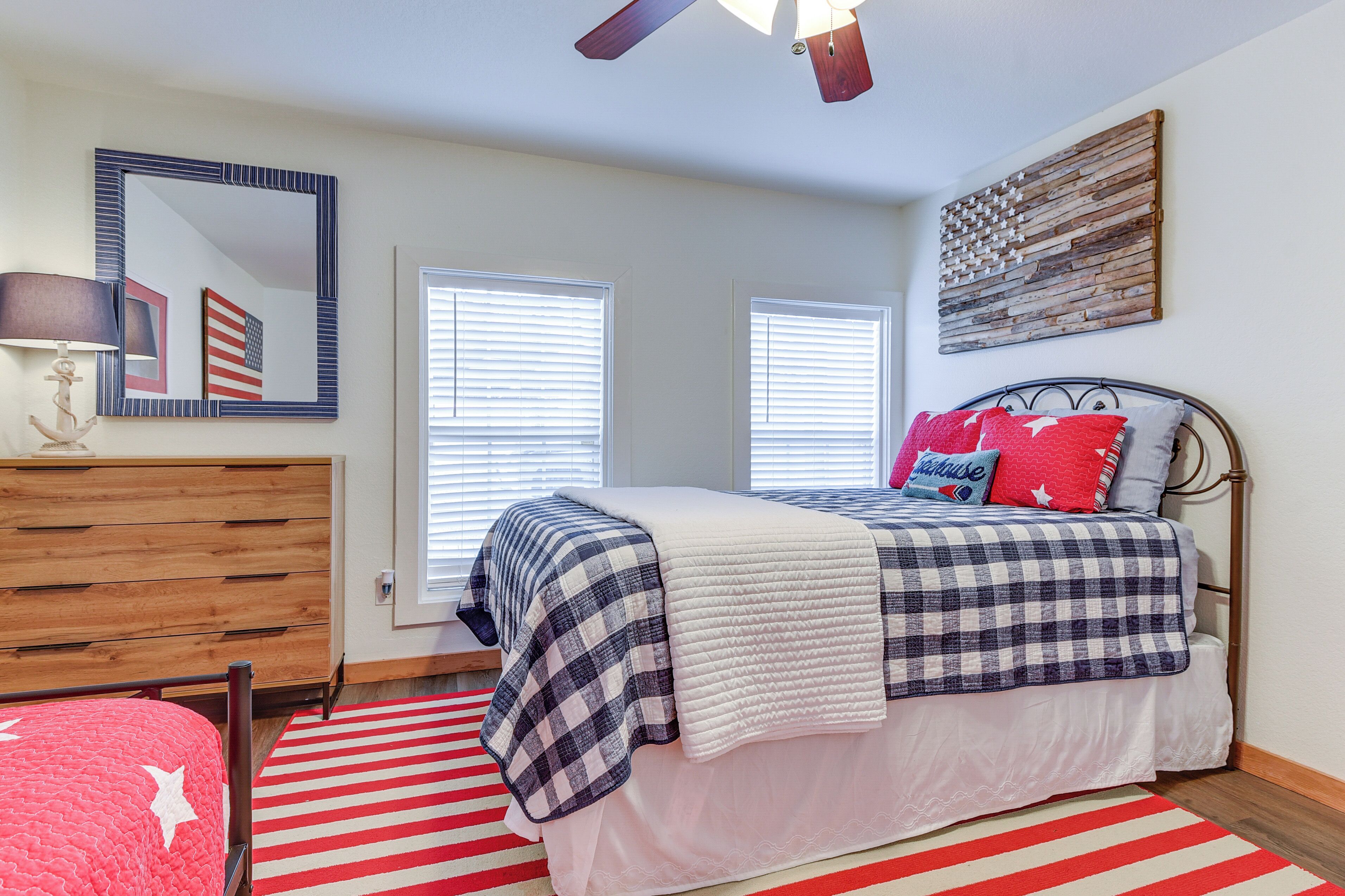 A bedroom with a bed, dresser, and a window with blinds.