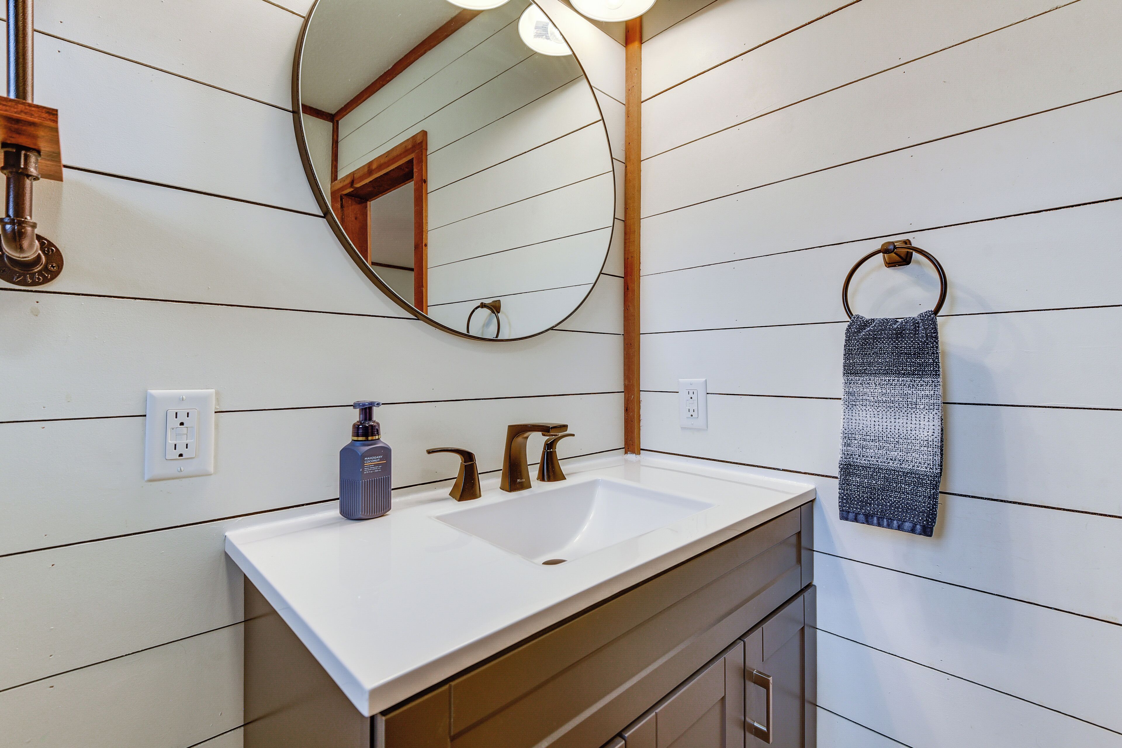 A bathroom with a white sink, a round mirror, and a towel ring.