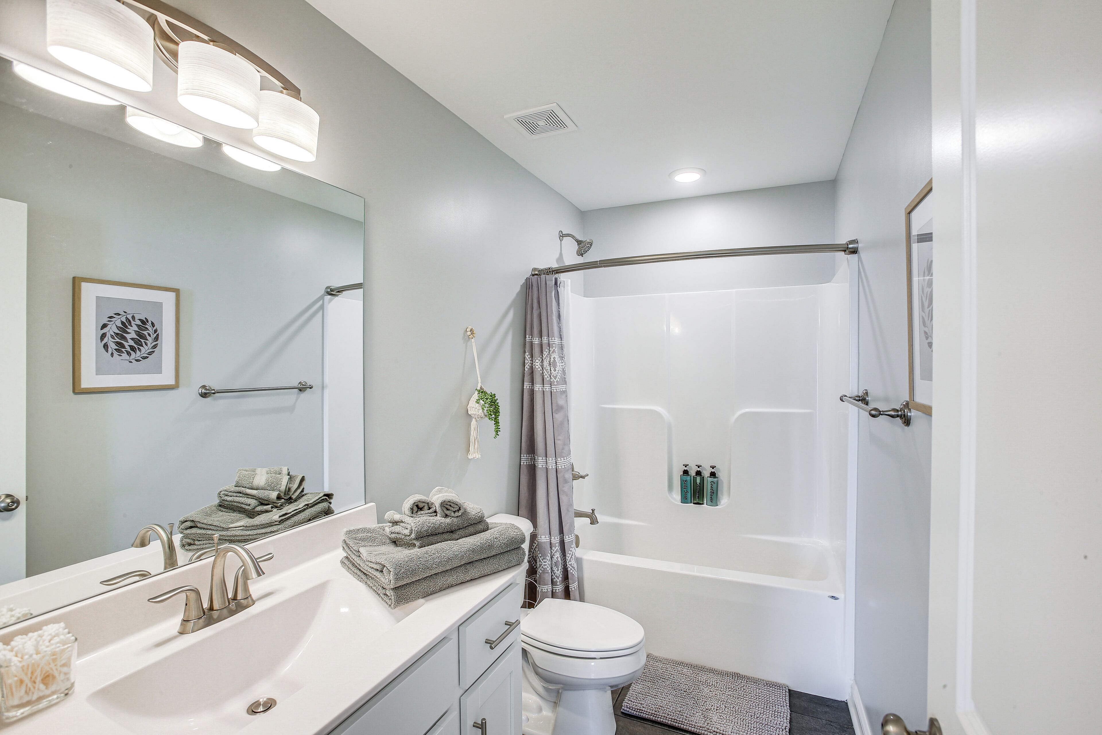 A modern bathroom with a large sink, a toilet, a shower with a glass door, and a towel rack.