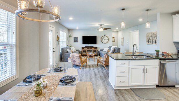 A modern kitchen with white cabinets, a stainless steel dishwasher, and a dining area with a wooden table and chairs. - Lovely Scottsville Home, Minutes to Bowling Green (Scottsville)