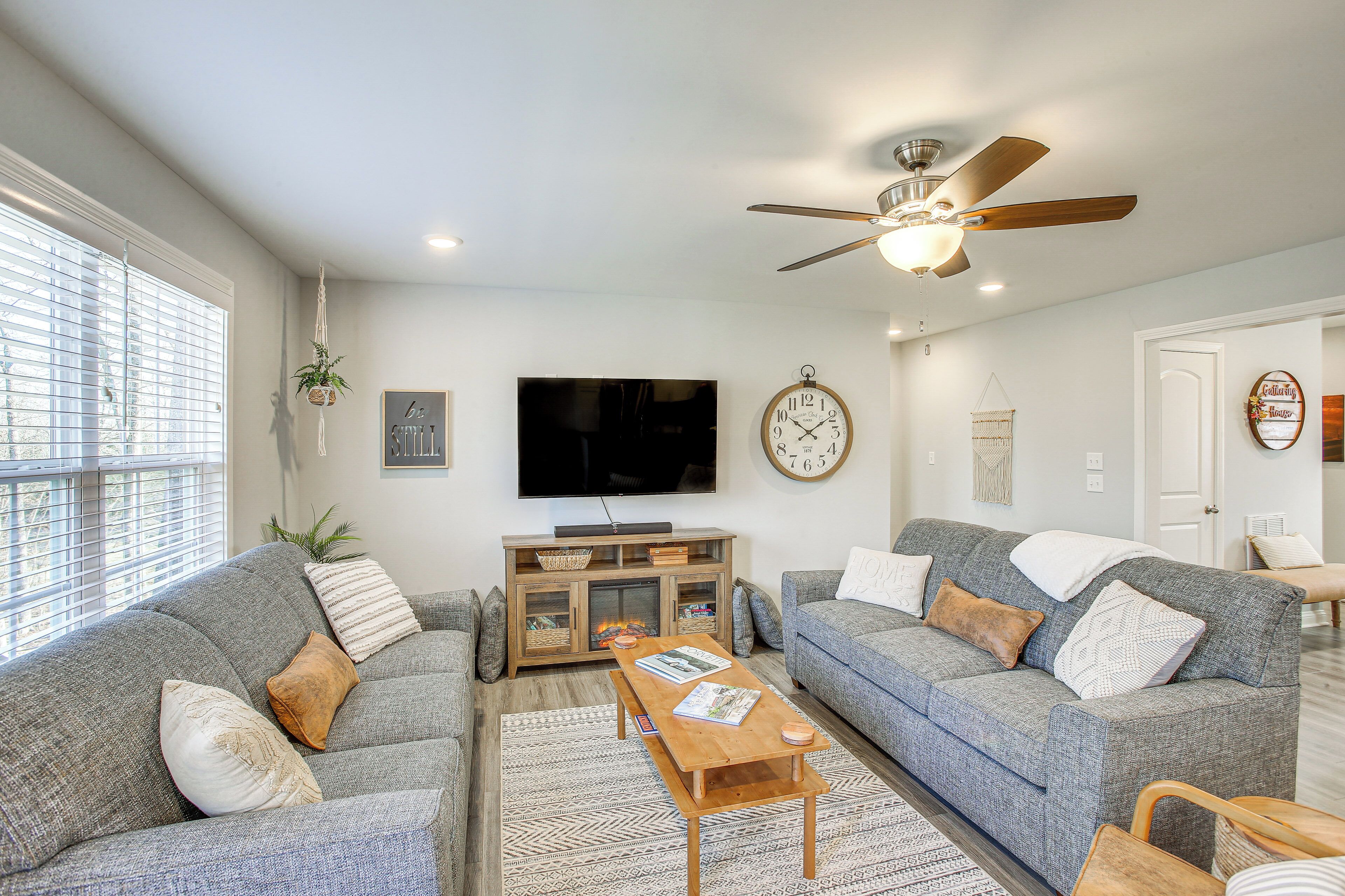 A living room with two grey sofas, a wooden coffee table, a TV, and a ceiling fan.