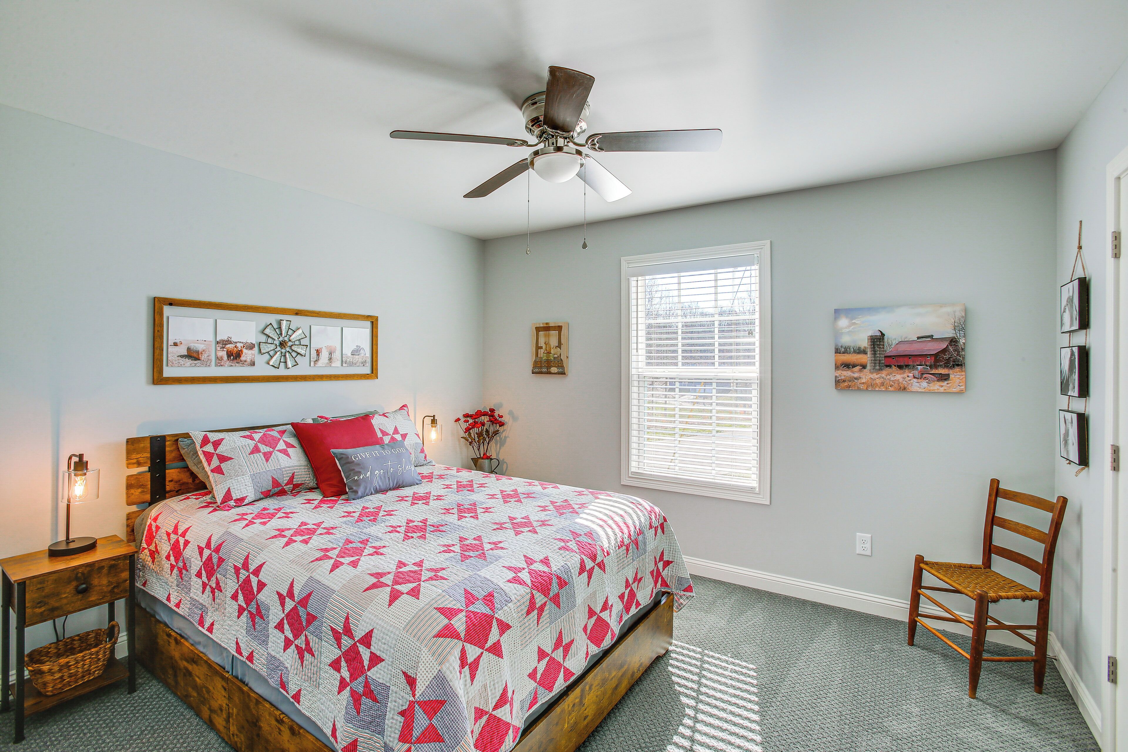 A bedroom with a bed, a ceiling fan, a window, and a chair.