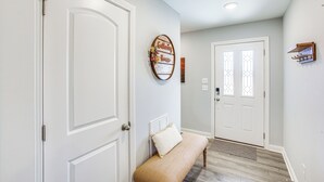 A hallway with white doors, a bench, a wall-mounted sign, and a small shelf. - Lovely Scottsville Home, Minutes to Bowling Green (Scottsville)