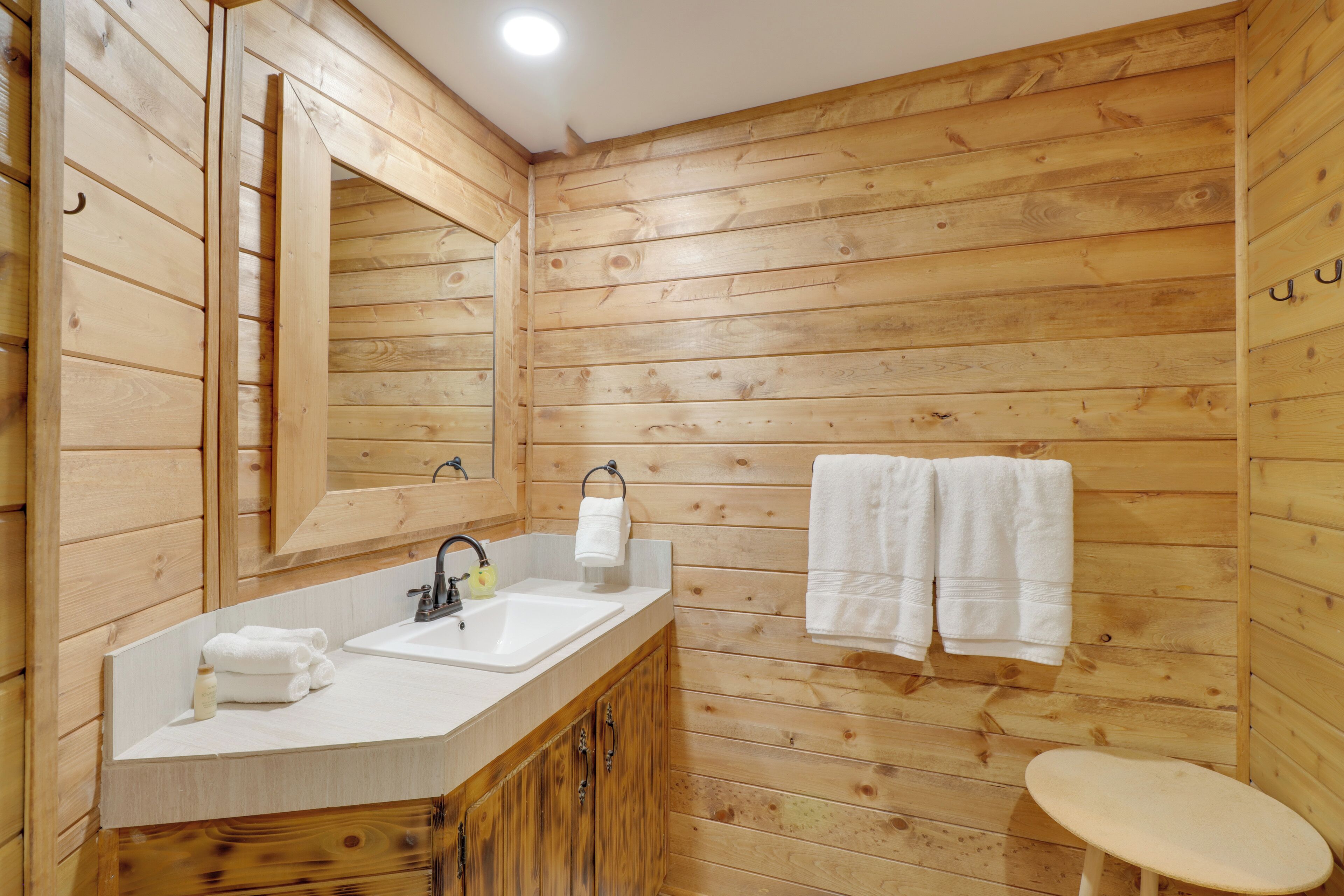 Un baño estilo cabaña de madera con un lavabo, un espejo y dos toallas colgadas en la pared.
