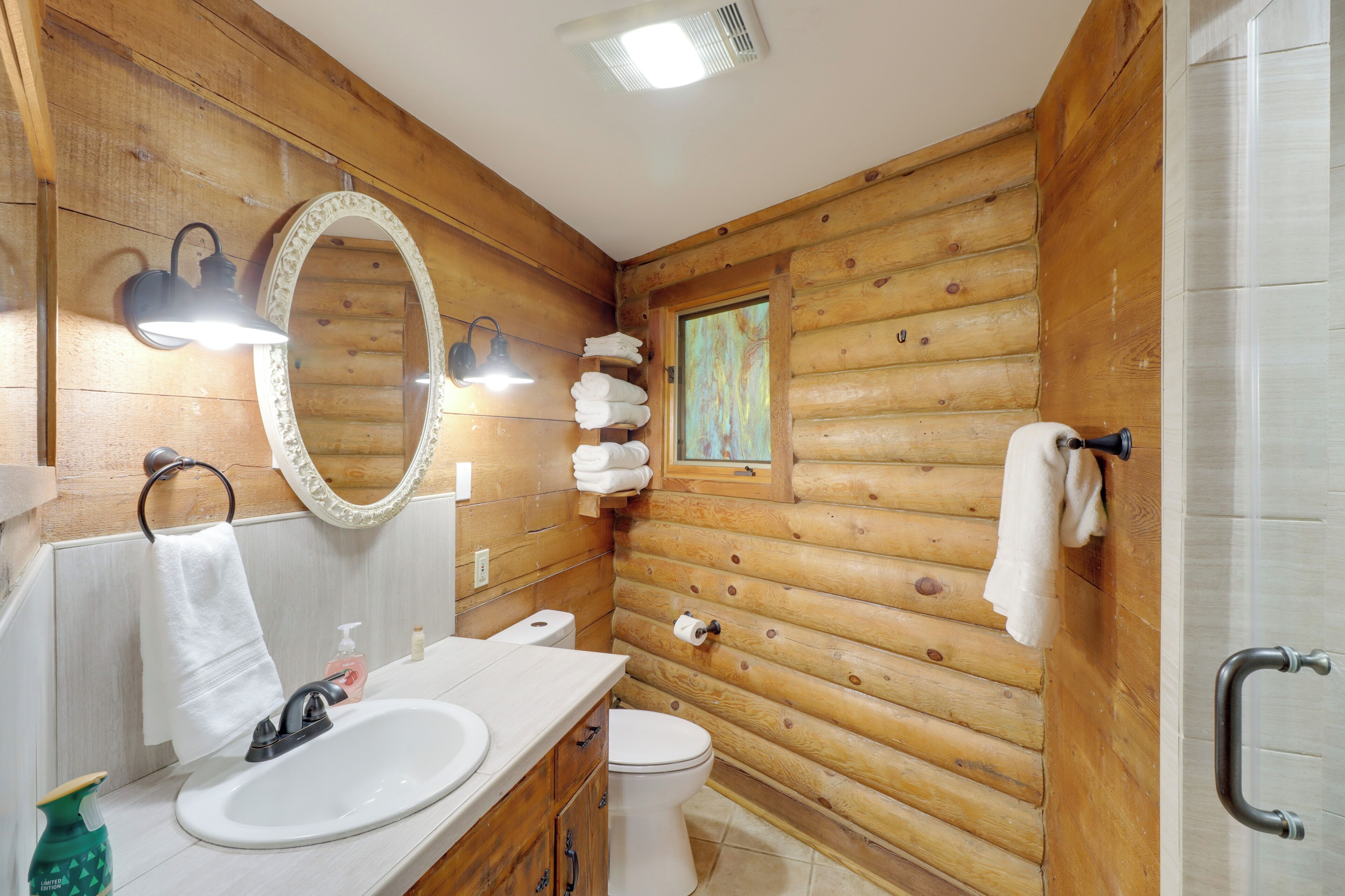 A wooden cabin bathroom with a sink, toilet, and mirror.