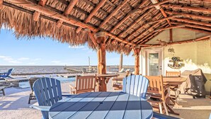 Un espace extérieur abrité, avec une table et des chaises, donnant sur la plage.