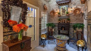 A traditional interior with a large ornate mirror, a tiled wall, a decorative bathtub, and a variety of potted plants. - Estudio en Casa Palacial (Sevilla)