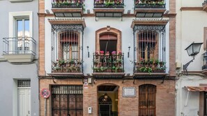 A building with multiple balconies, each adorned with potted plants. - Estudio en Casa Palacial (Sevilla)