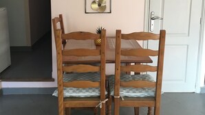 Een eetgedeelte met een houten tafel en stoelen, een lijst met decoratieve afbeelding en een witte deur op de achtergrond.