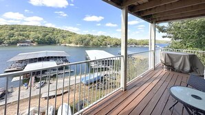 A wooden deck with a view of a lake and docked boats. - Wheelhouse: Lakefront 2BD/3BA/Deck/Pool/Pet Friendly-6PP (Lake Ozark)