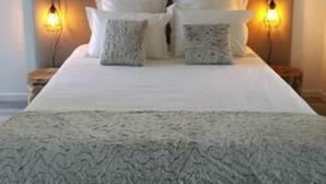 A bed with pillows, a wooden headboard, and two wall-mounted lamps.
