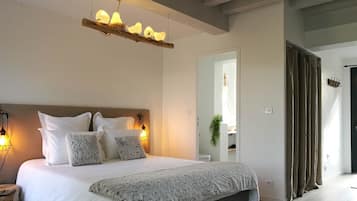 A bedroom with a large bed, two wall-mounted lamps, a hanging light fixture, and a mirror.