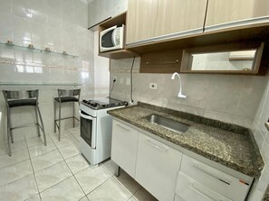 Comfort appartement | Privékeuken | Een koelkast, een microgolfoven, een oven, kookgerei, borden en bestek