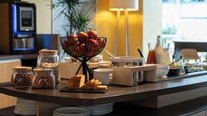 Un buffet della colazione con diversi cibi e condimenti, tra cui frutta, pane e bevande.