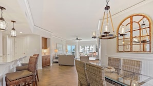 A spacious living area with wicker furniture, a glass dining table, and a large arched window. - Oceanfront 2 bedroom villa in Palmetto Dunes with Community Pool (Hilton Head Island)