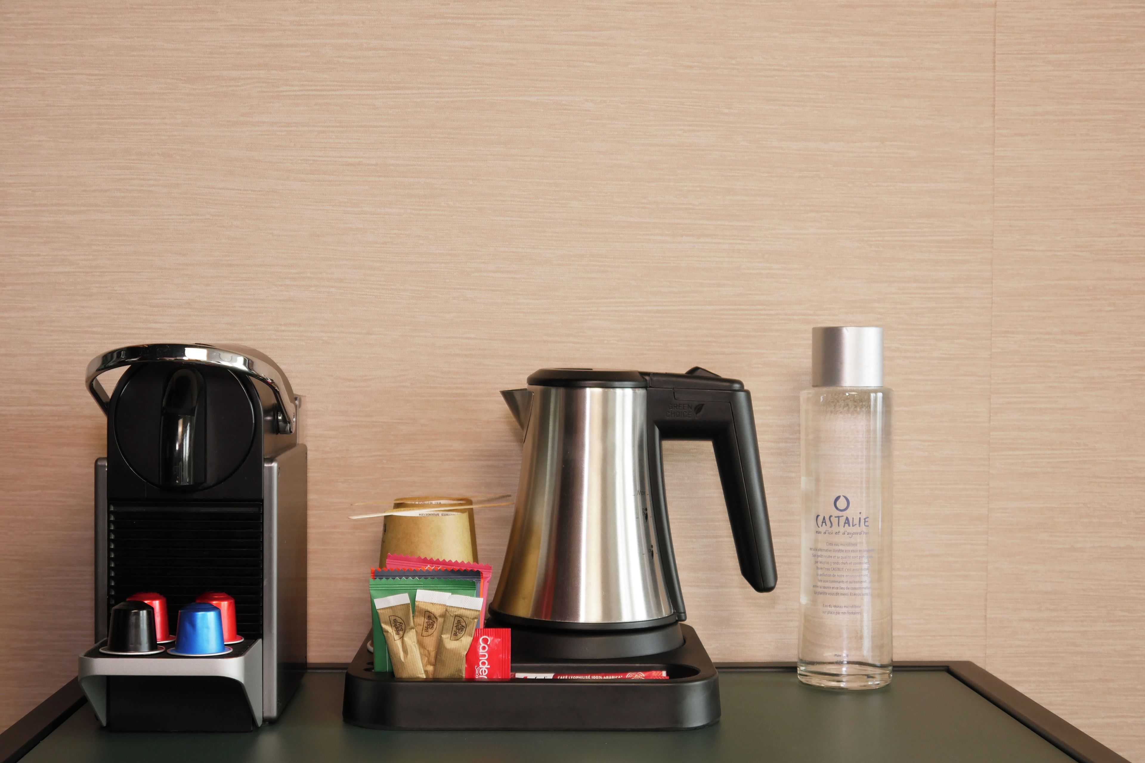 Una cafetera, un hervidor, una botella y un dispensador de cápsulas de café sobre una mesa.
