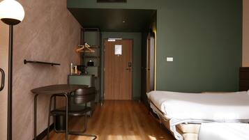 A hotel room with a bed, a desk, a chair, a wardrobe, and a hanging coat rack.
