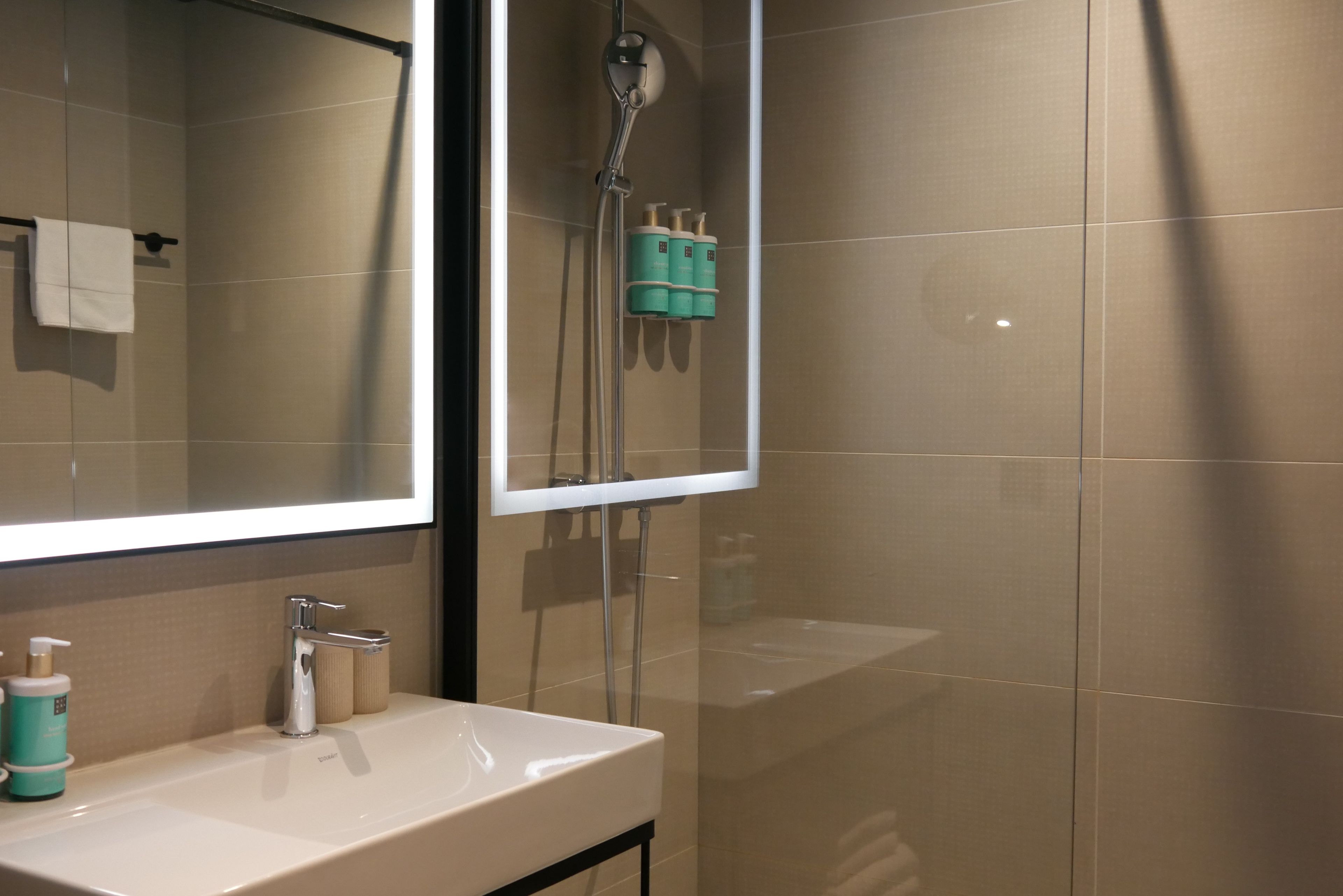 A bathroom with a sink, mirror, and shower.