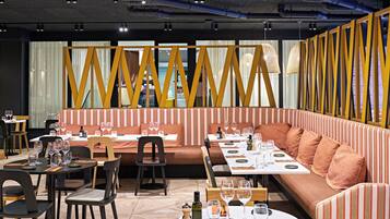 A restaurant with tables set for dining, a sofa area, and a view through a patterned partition.