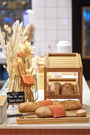 A bakery display with various breads and pastries, a sign indicating 'Pain de mie Toast bread', and a decorative arrangement of dried plants. - Novotel Rouen Centre Cathédrale (Rouen)