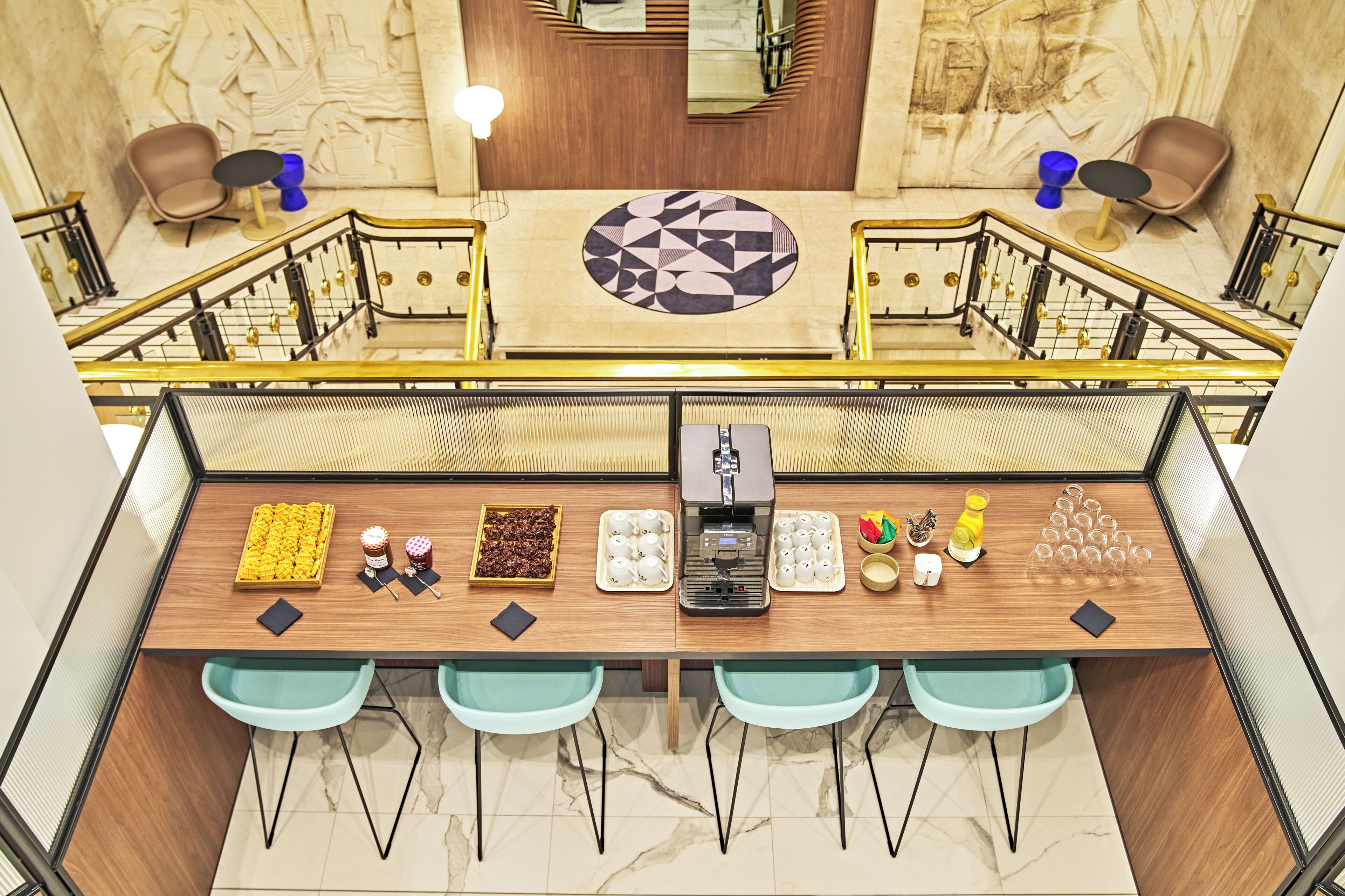 Un moderno vestíbulo de hotel con una barra de café central, zona de estar y una pared decorativa.