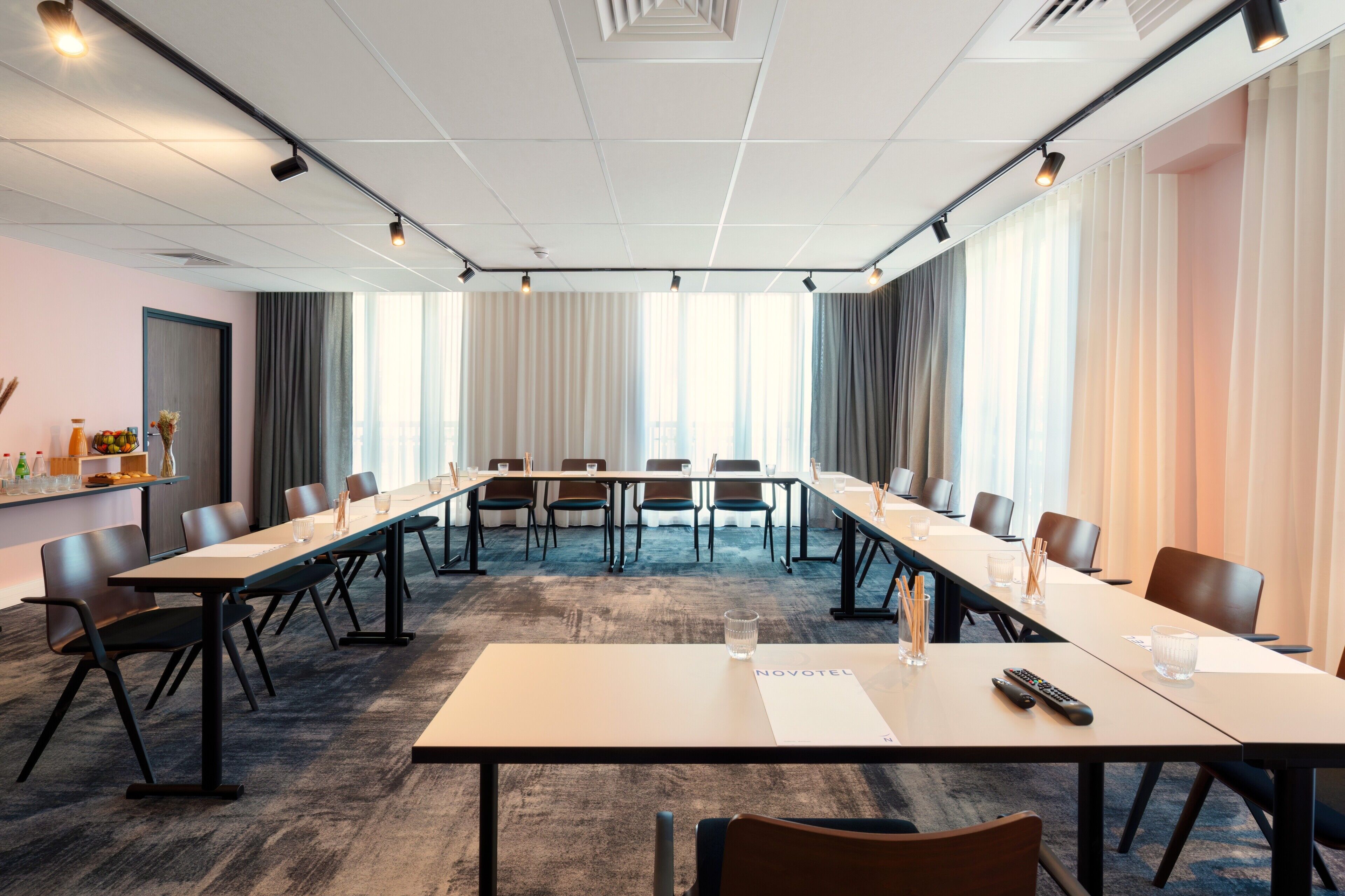 Un salón de conferencias con una larga mesa, sillas y un cartel que dice 'NOVOTEL'.