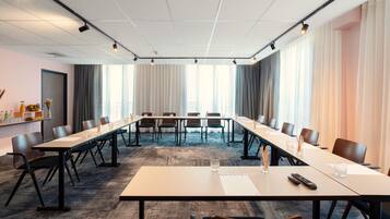 Un salón de conferencias con una larga mesa, sillas y un cartel que dice 'NOVOTEL'.