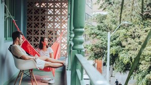 A balcony with a hammock, a railing, and a view of a street with a taxi. - Cama En Habitación Compartida Mixta En El Sector De La Candelaria - Medellín (Medellín)