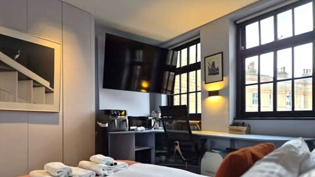 Ein Hotelzimmer mit Bett, Schreibtisch und einer Küchenzeile.
