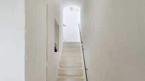 Eine enge, weiß getünchte Treppe, die zu einer Zwischenebene führt.